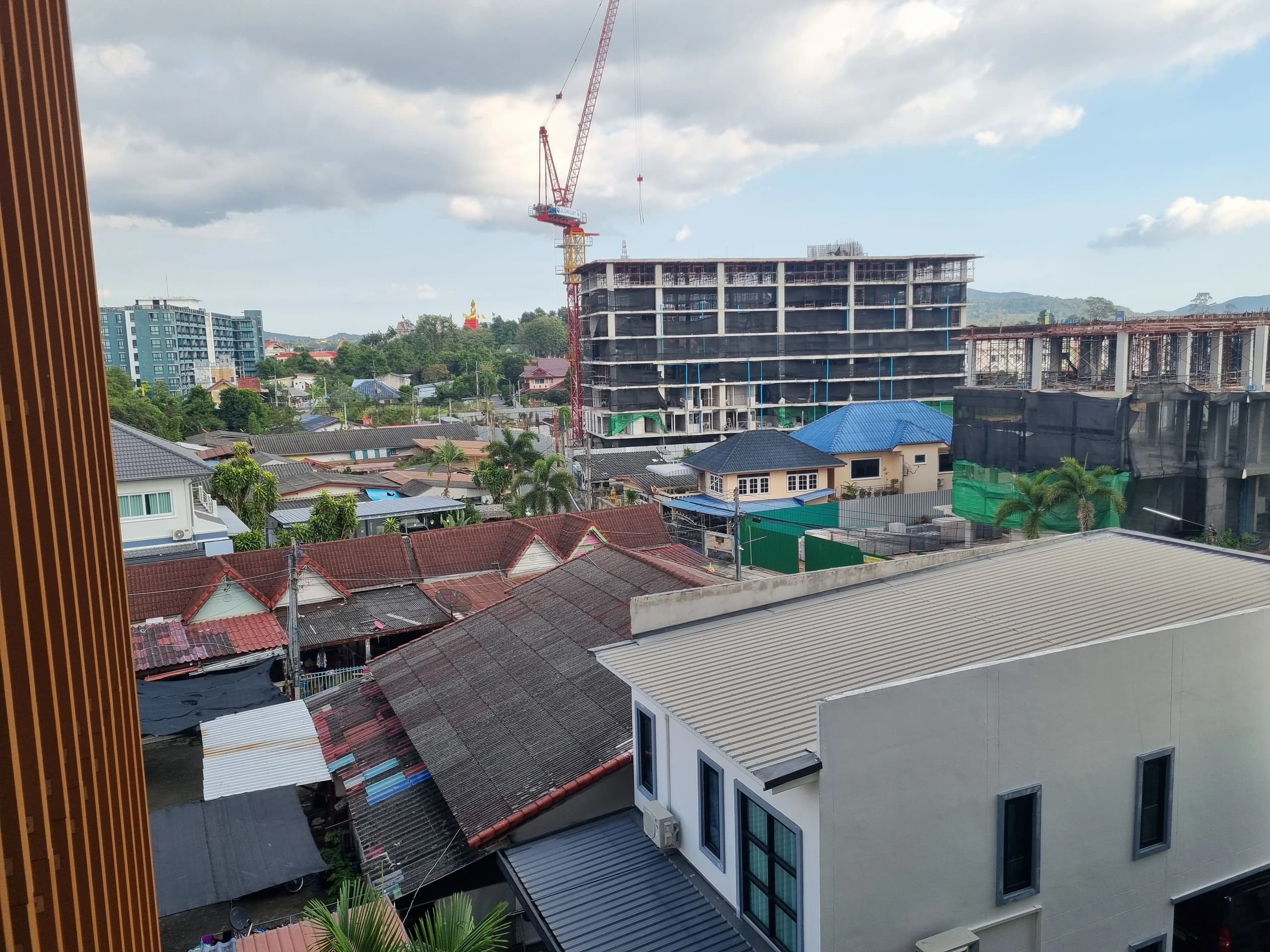 วิวจากระเบียง เห็นหลังคาบ้านในชุมชน ภูเขา และอาคารที่กำลังก่อสร้างบนที่ดินข้างเคียง